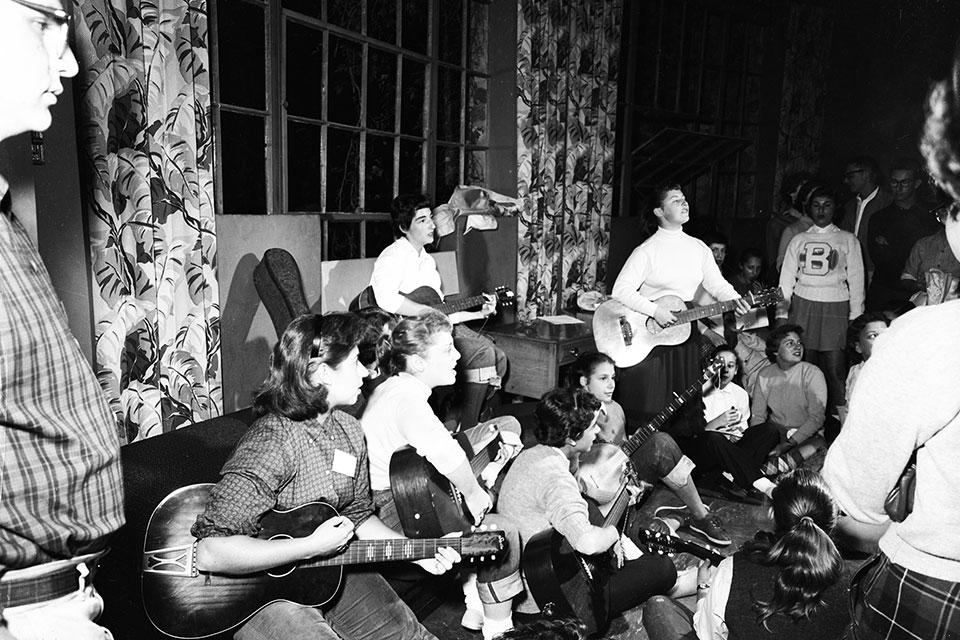 A group of students sing and play guitars in a room.