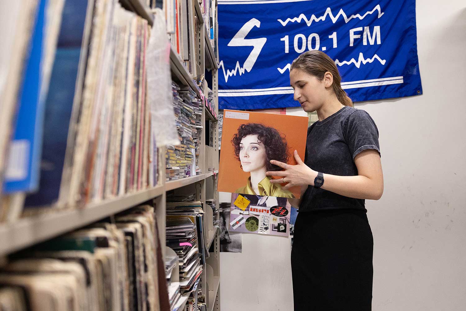 A student browses a shelf of records and CDs.