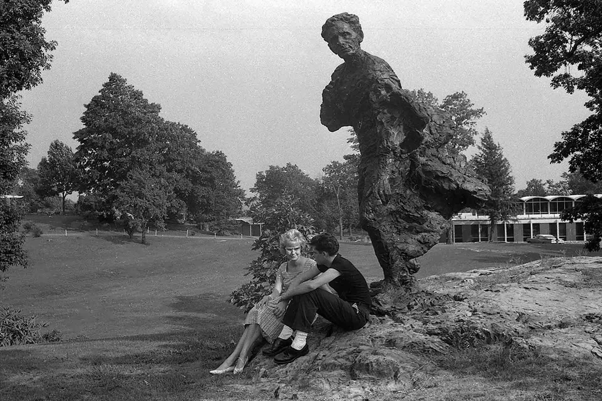 Black and white photo of students on campus with the Louis Brandeis statue