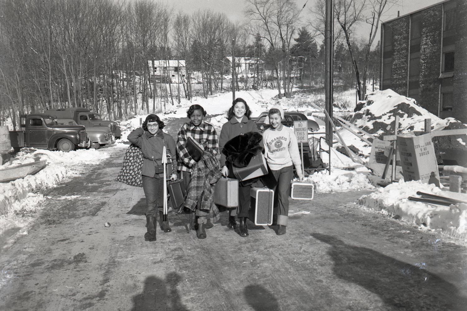 Black and white photo of people walking on campus with snow on the ground