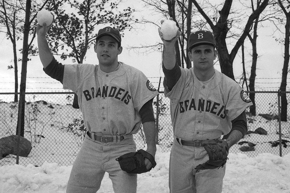 Two people in baseball uniforms throw snowballs