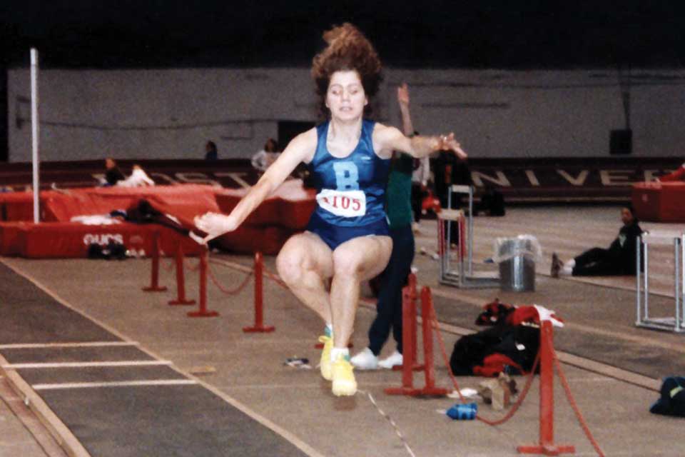 Athlete Eleena Zhelezov mid-air competing in the triple jump