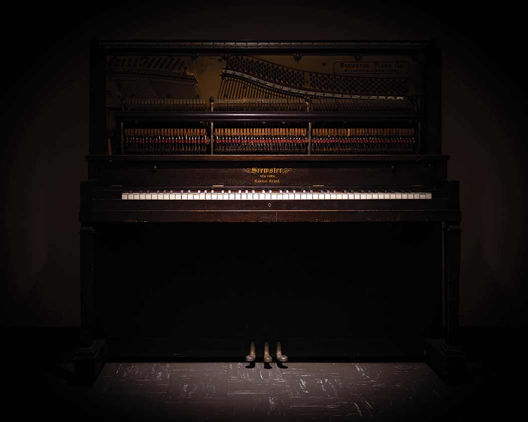 A shadowy photo of a brown upright piano.