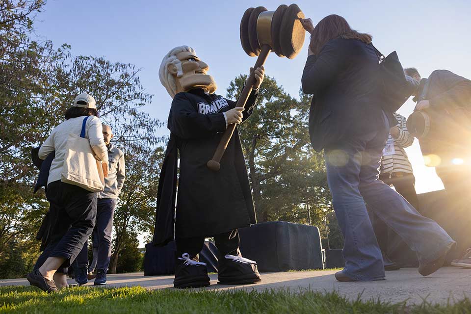 A person gives the Judge mascot a high five with the gavel