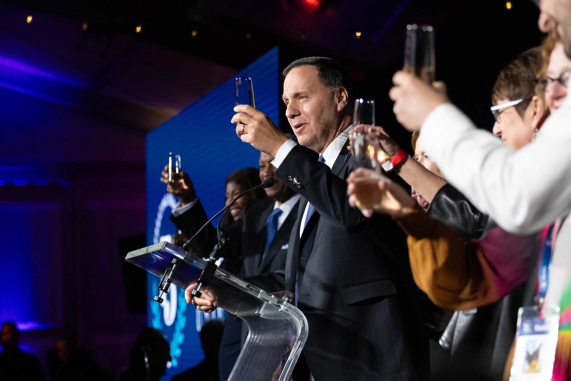 People stand on a stage and raise glasses for a toast.