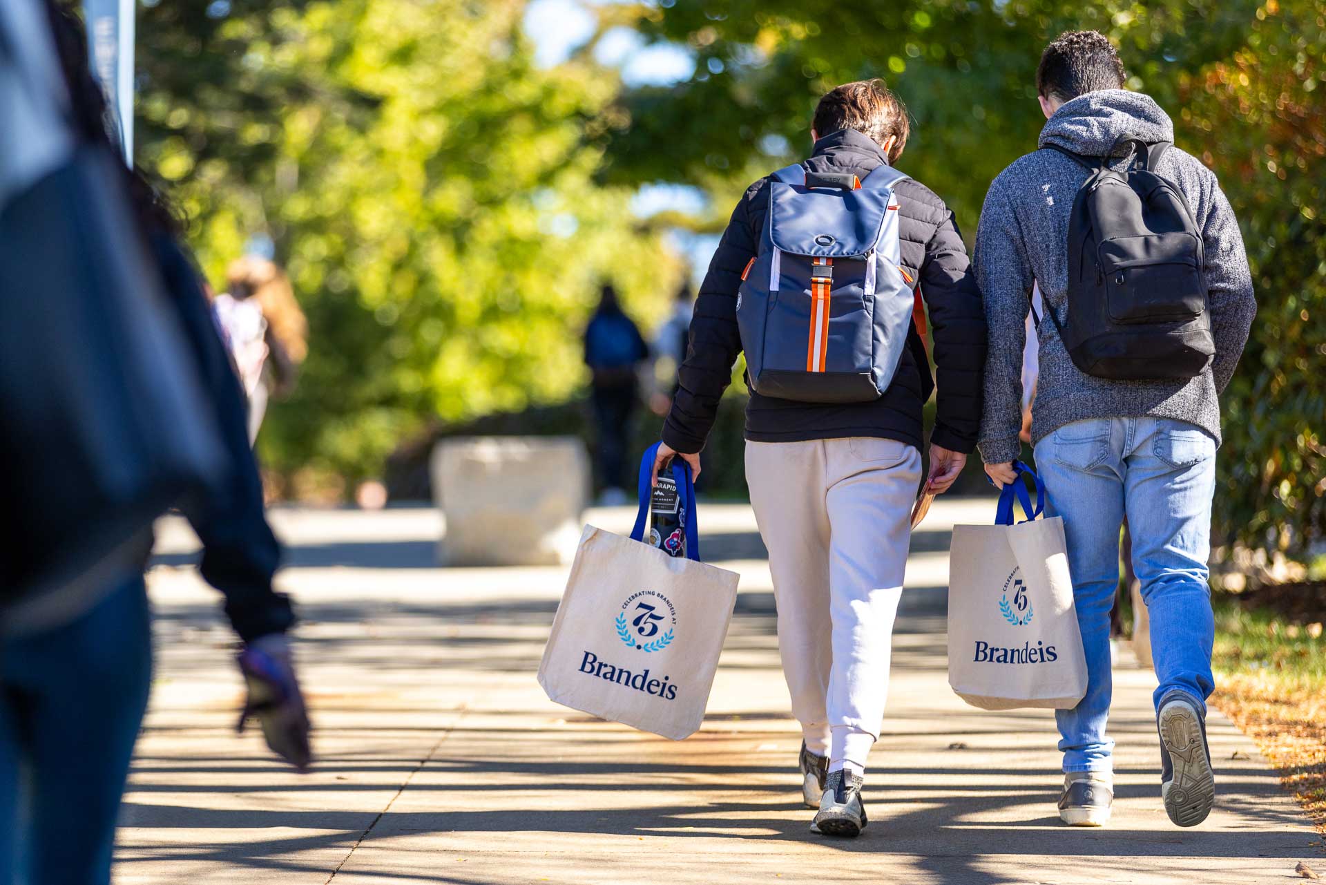 People walk with tote bags along a path.