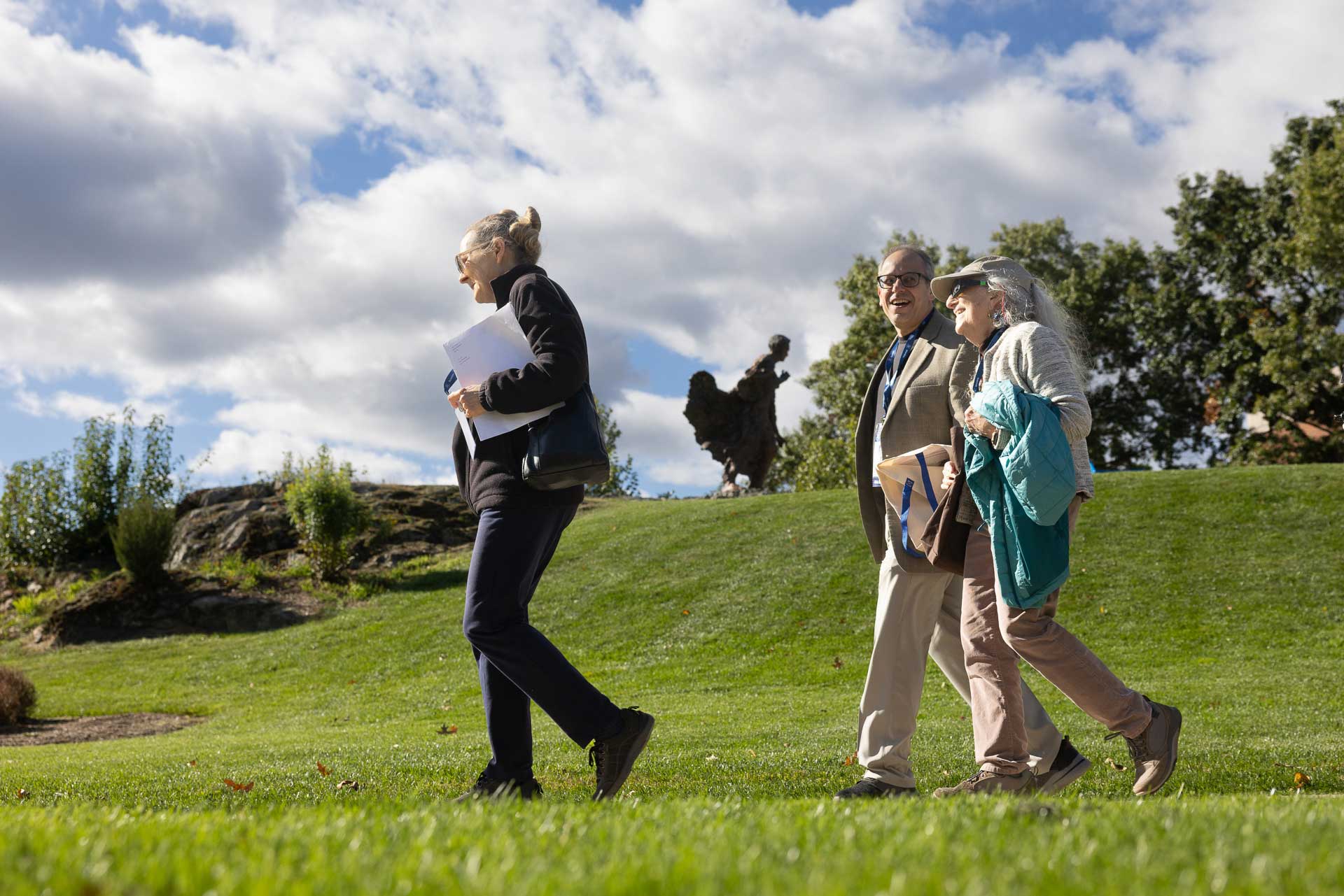 Three people walk passed a statue of Louis Brandeis