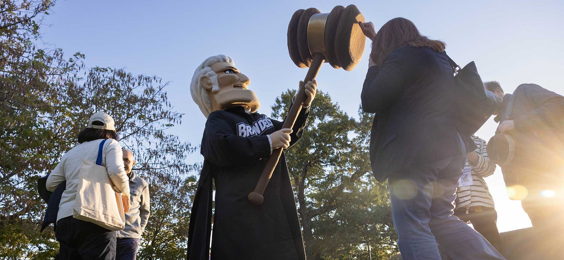 A person high fives the Brandeis Judge mascot's gavel