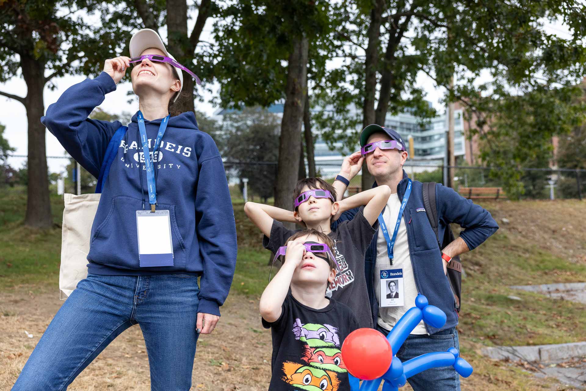 Two parents and two children look at the sky with protective eclipse glasses.