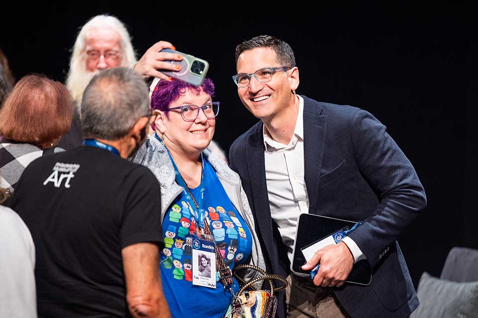 An audience member takes a selfie with Guy Raz