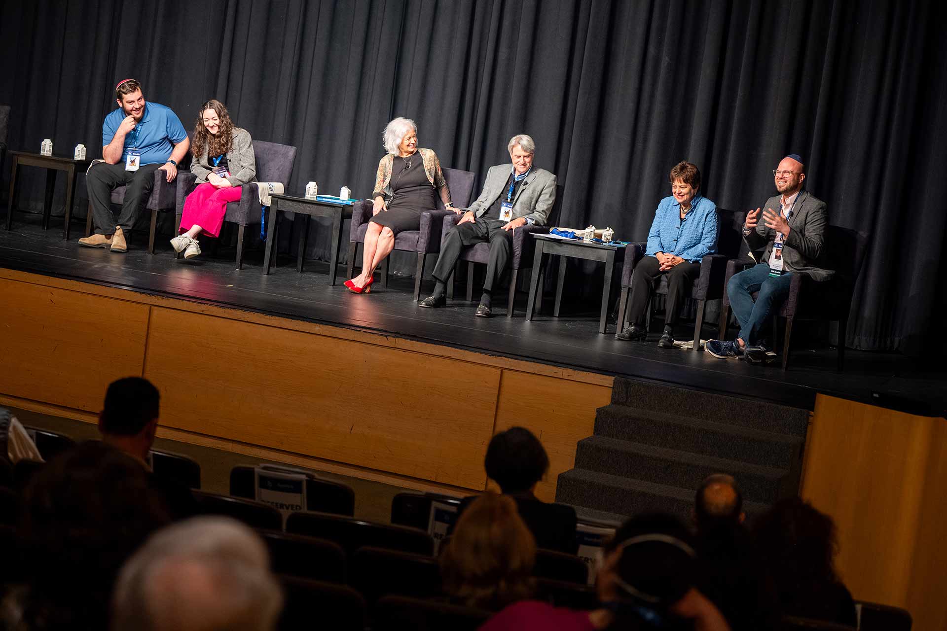 Six people on stage share a laugh