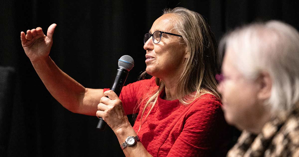 Dorothee Kern speaks into a microphone, one arm outstretched