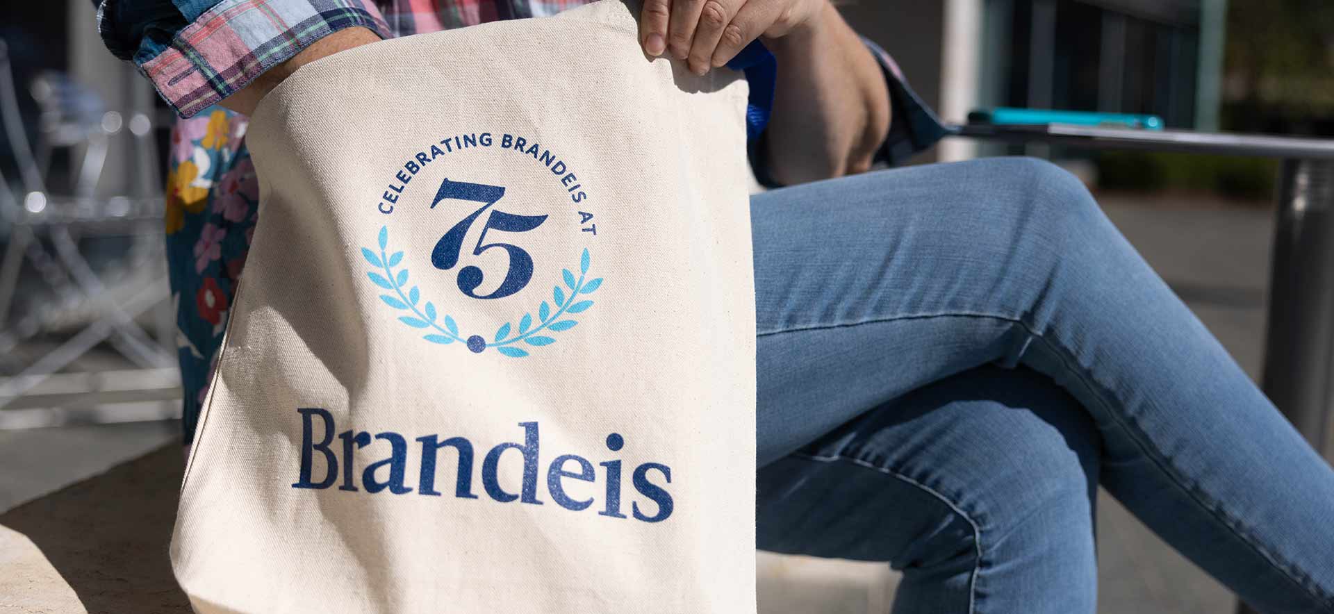 Person sits with a 75th anniversary tote bag