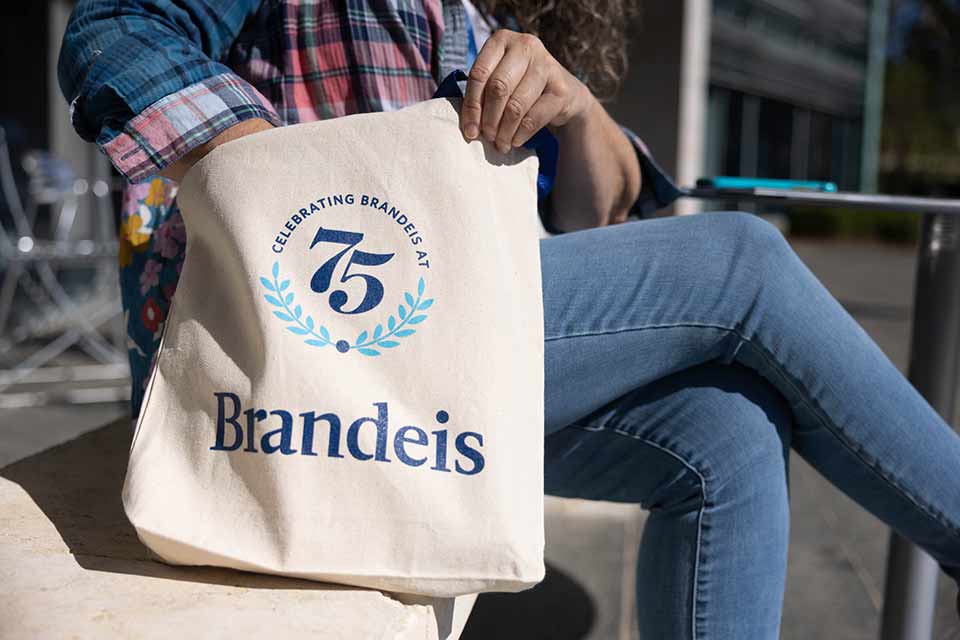 Person sits with a 75th anniversary tote bag