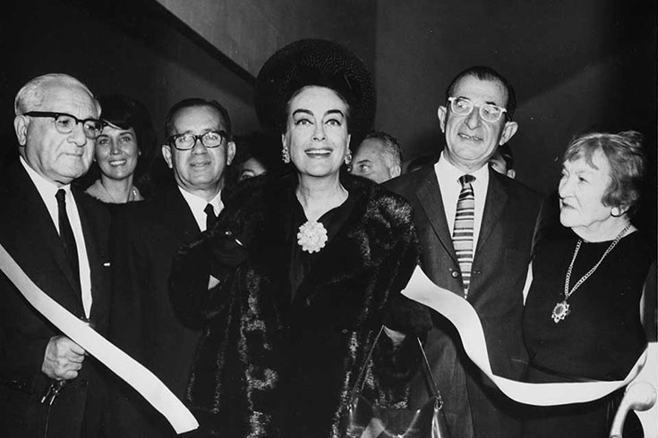 Joan Crawford surrounded by people at a ribbon cutting ceremony