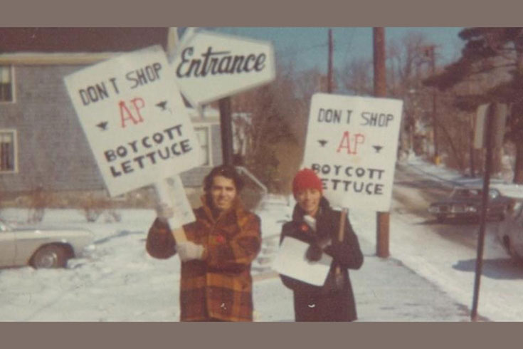 Elvira Castillo, right, dons a heavy coat and cap, holds a sign that reads, “Don’t Shop AP. Boycott Lettuce,” alongside a graduate student.
