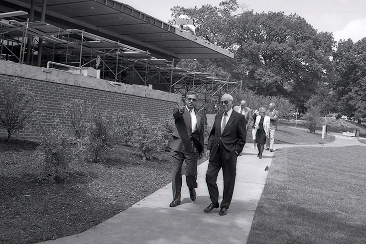 Two people walk by the construction of the Shapiro Admissions Center