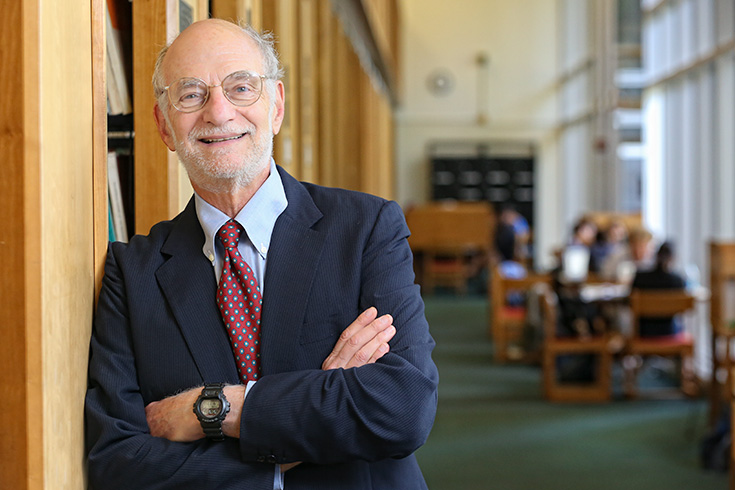 Michael Rosbash leaning against library stacks with his arms crossed