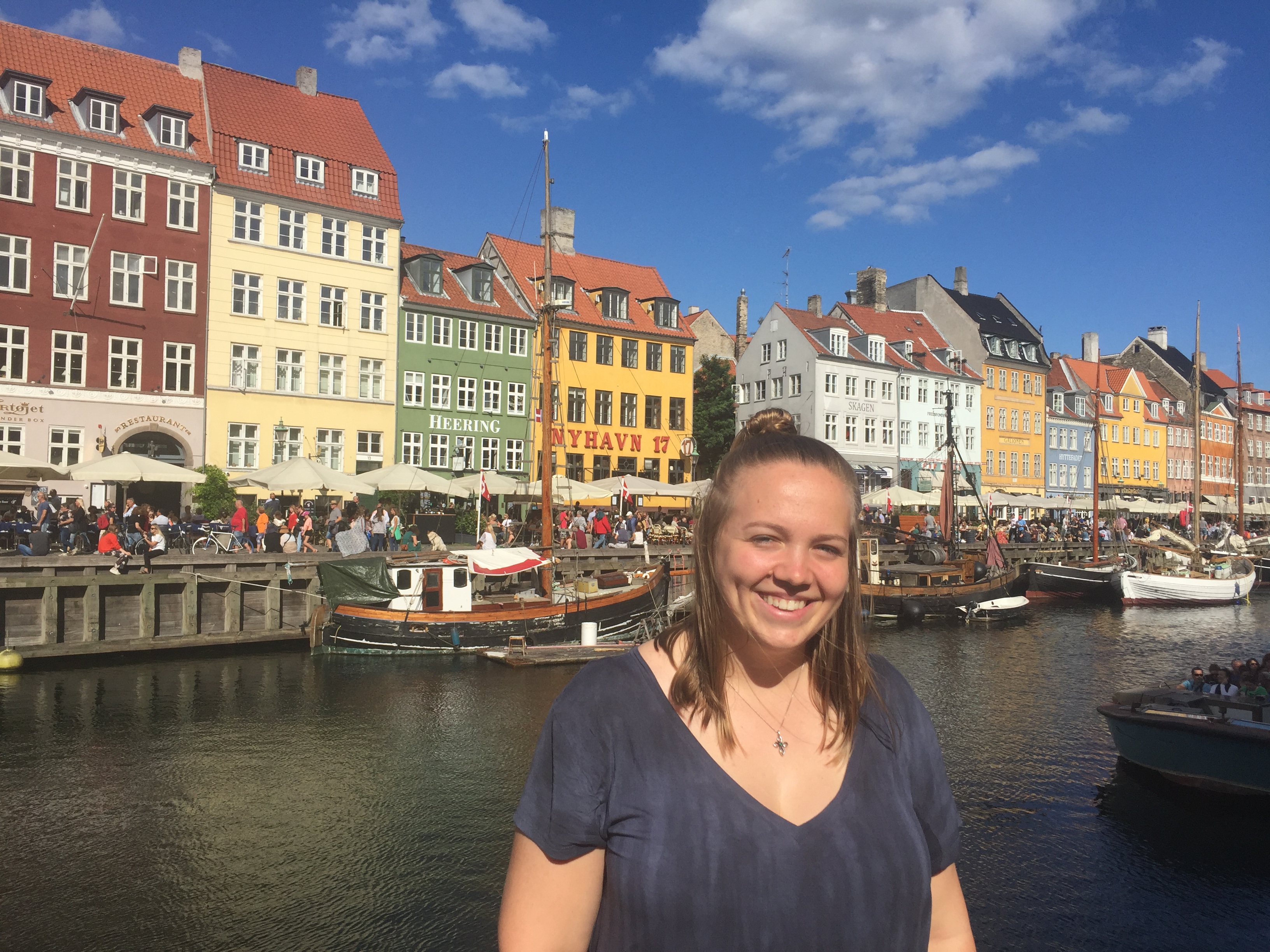 Caylee standing in front of a row of colorful houses on a sunny day in Copenhagen..