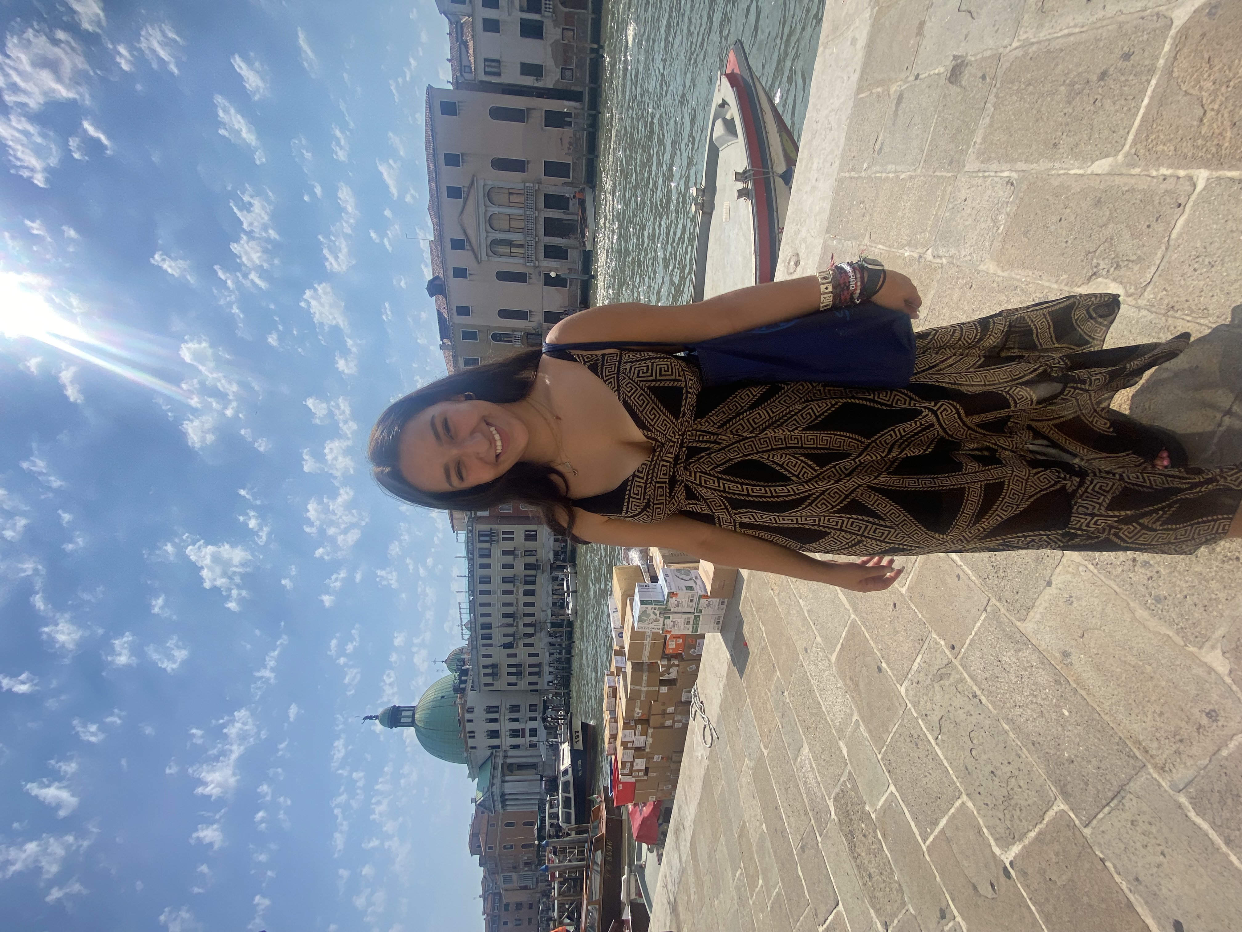Allison standing smiling in front of a river in Italy on a sunny day.