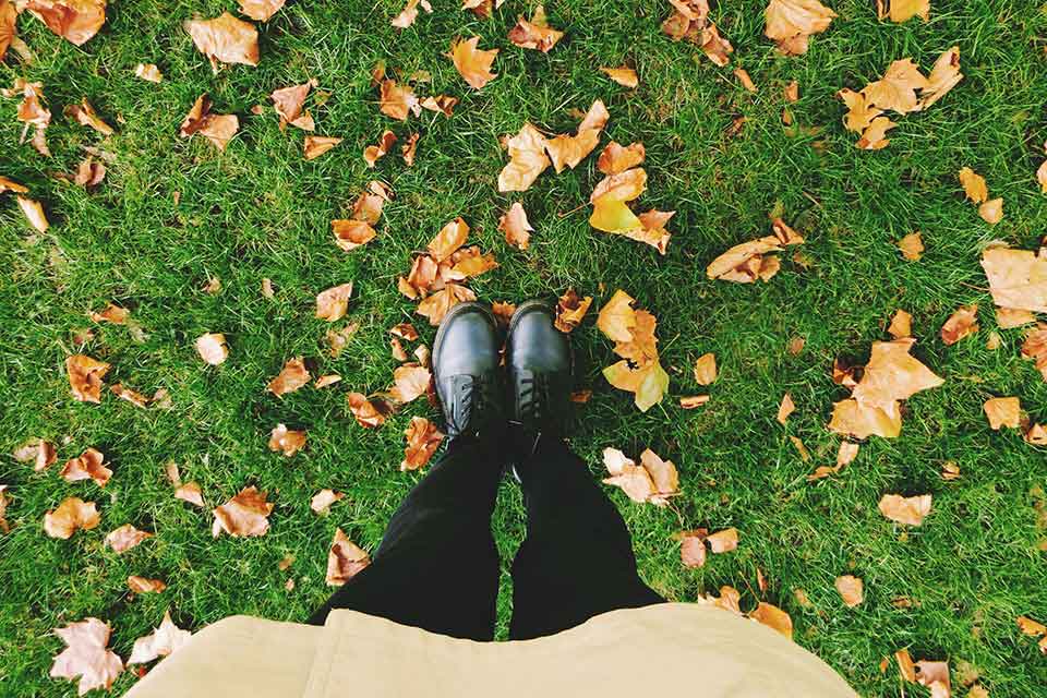 A student stands in the fall leaves and grass