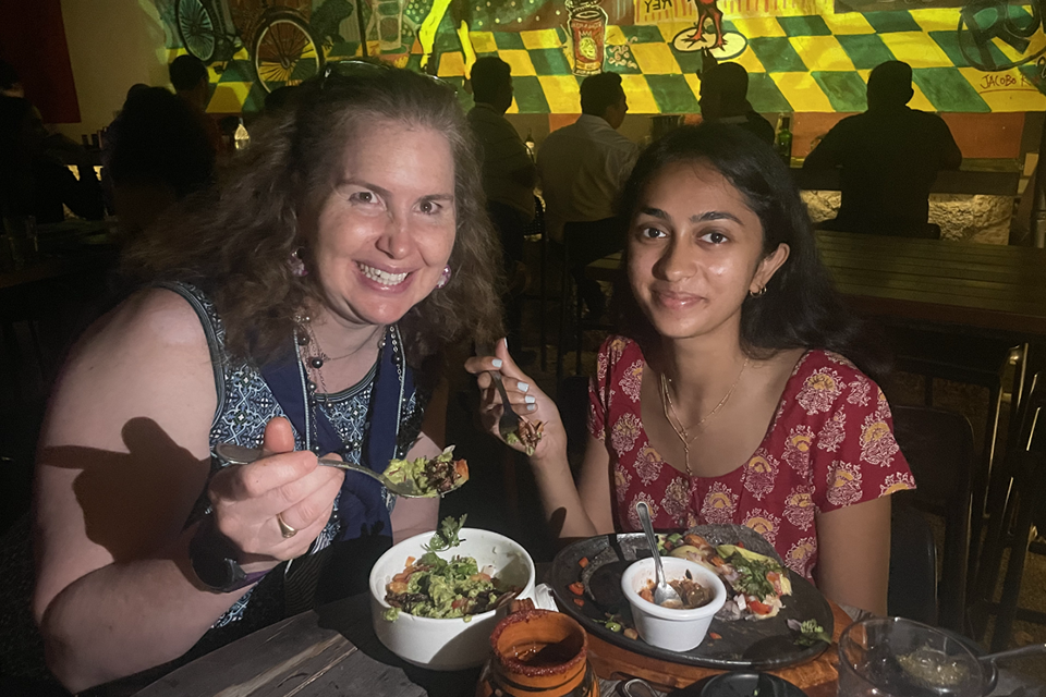 Sarah Curi and a student sit at a table with food in Merida, Mexico