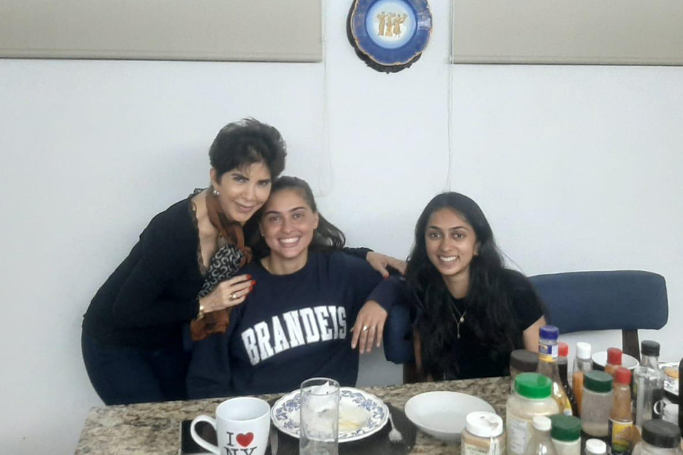 Two Brandeis students seated at the dinner table with their local host mother