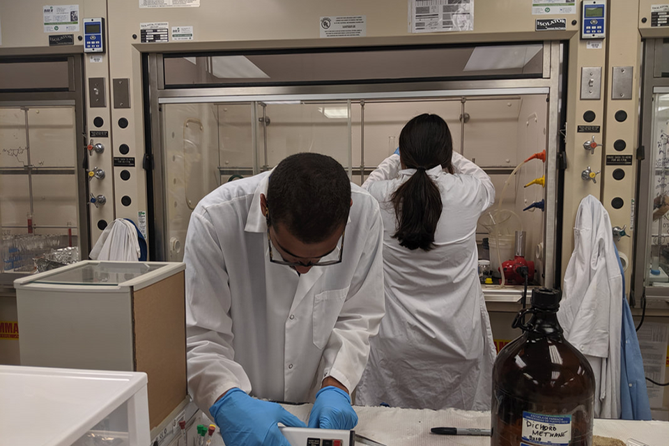 Two students conducting experiments in a lab wearing white coats