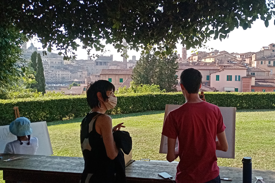 Professor Franca Marini instructs a student in front of a canvas on painting the Siennese landscape