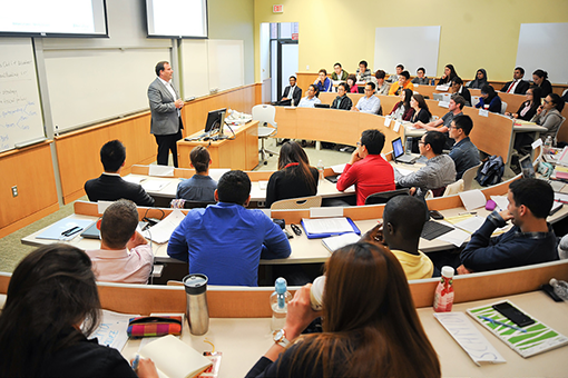 Students sit in a classroom while a professor delivers a lecture