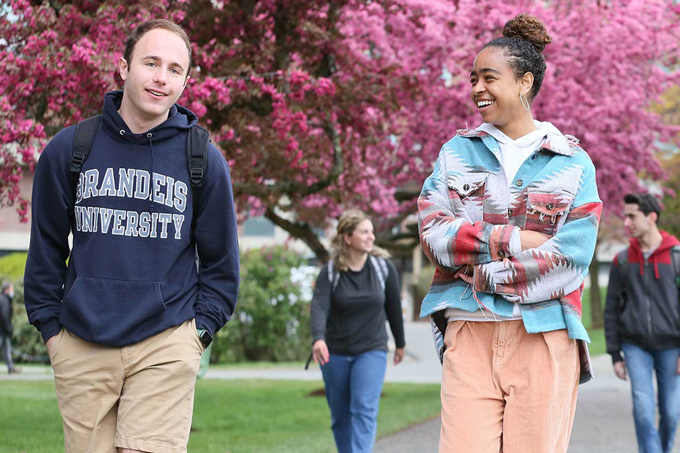 Two students walk up Brandeis' campus