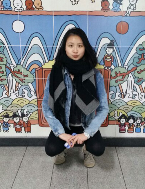 Yini Rong sits in front of a mural in South Korea