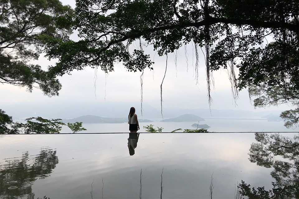 Stephanie standing in front of a pool in front of the bay of Hong Kong