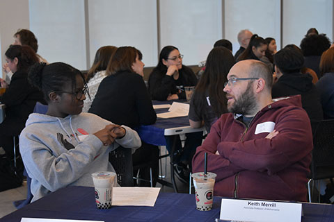 A professor and student sit at a table talking.