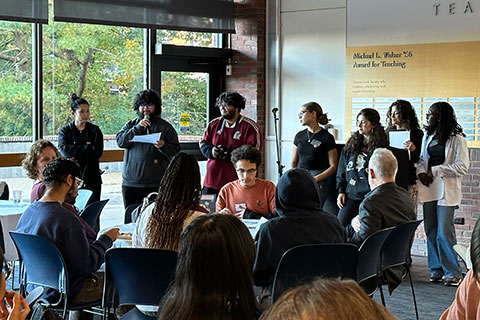 A student speaks into a microphone in front of an audience.