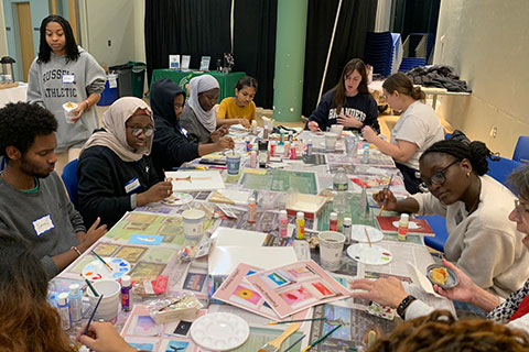 A group of students paint at a table.