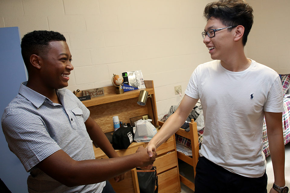 Two students shaking hands in a residence hall