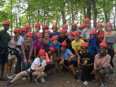 A group of students outdoors wearing red hard hats