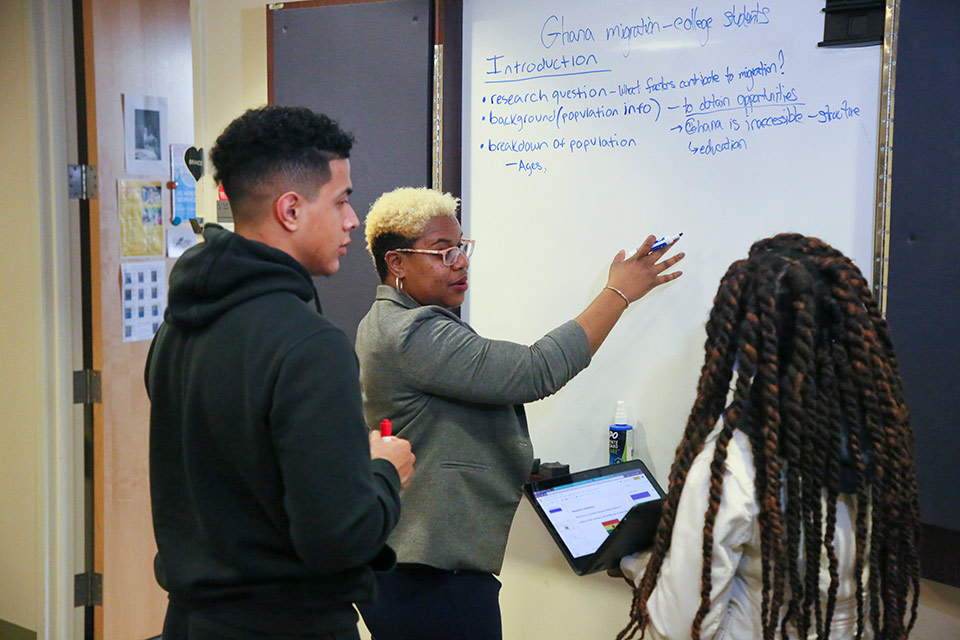 Students and staff working together at a whiteboard