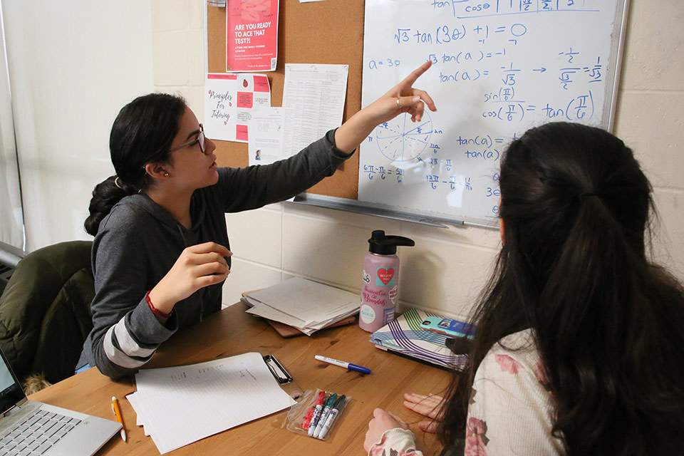 Two students working through a math problem at a whiteboard