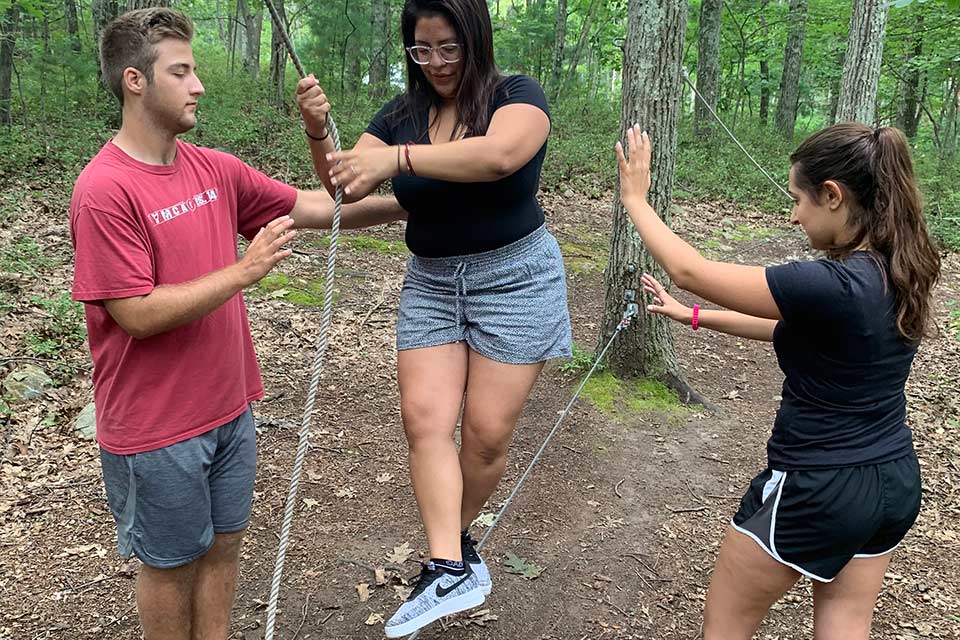 Students in the woods walking on a rope