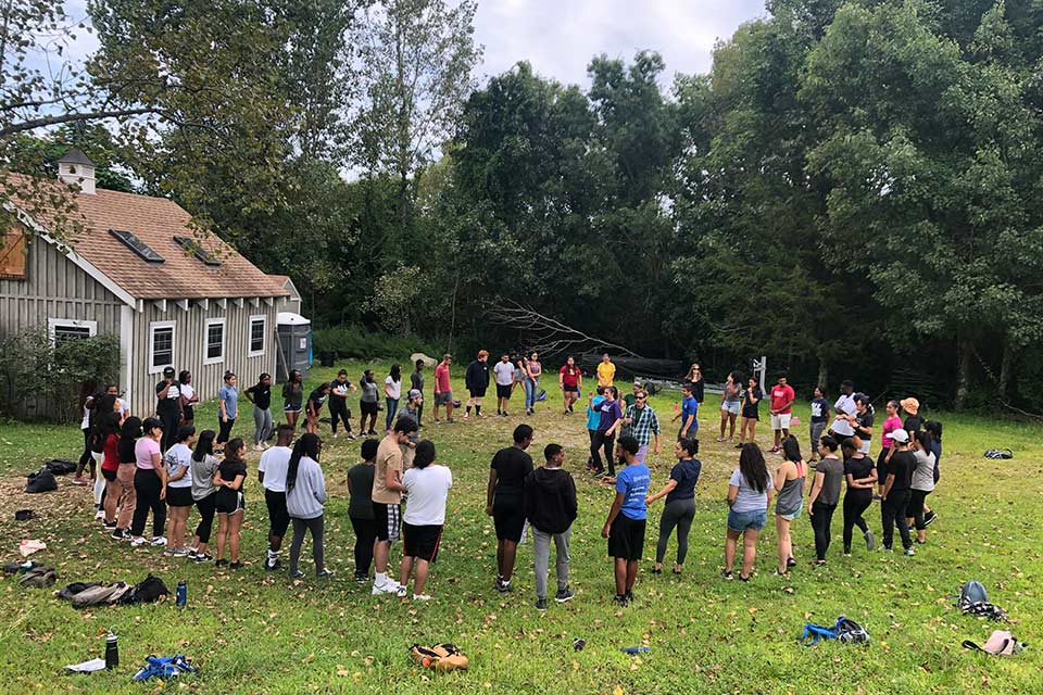 Circle of happy students in a field next to a house