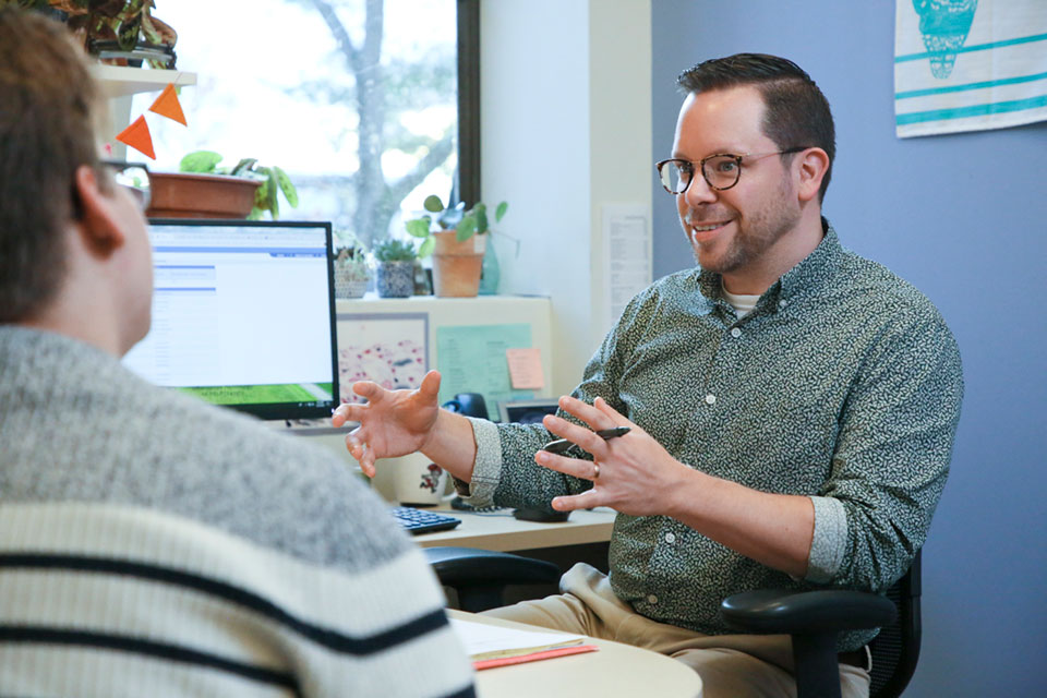 An academic advisor sits and talks with a student