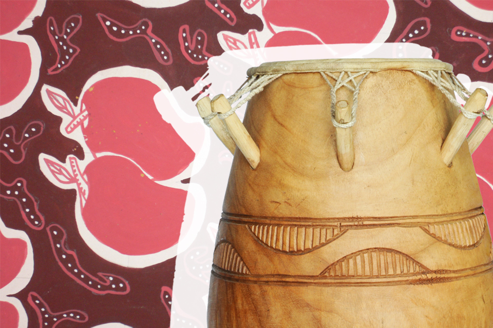 A wooden drum in the foreground with a patterned pink and maroon illustration in the background