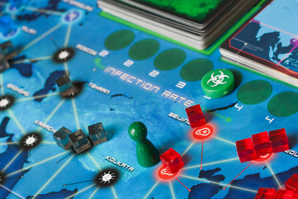 Close up of the board game Pandemic, that shows mutlicolored pieces on the board.