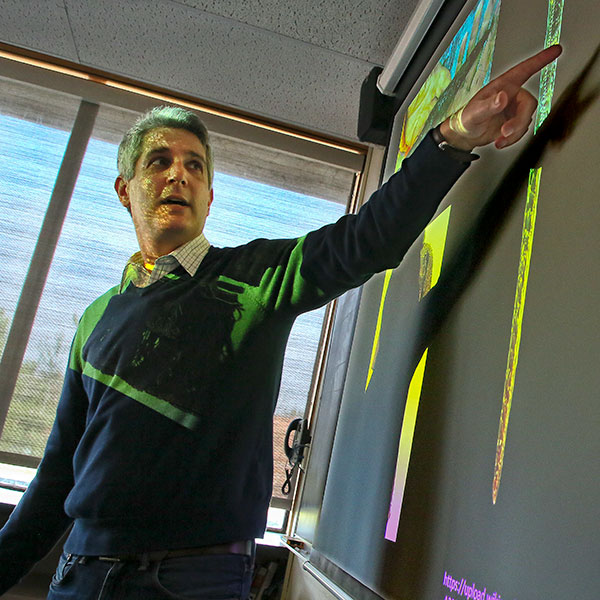 Charles Golden points up at a board during class