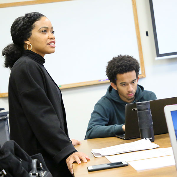 Amber Spry standing at a seminar table with a student seated at the table