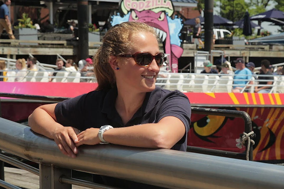 A student wearing sunglasses smiling, standing on a boat