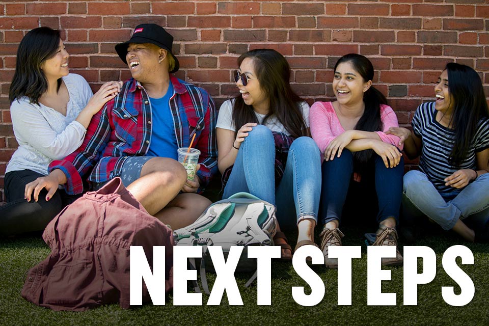 Five happy students sitting against a brick wall, with text that reads, "Next Steps"