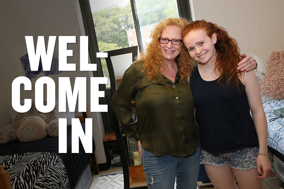 A student and family member in a residence hall, with text that reads Wel-come In.